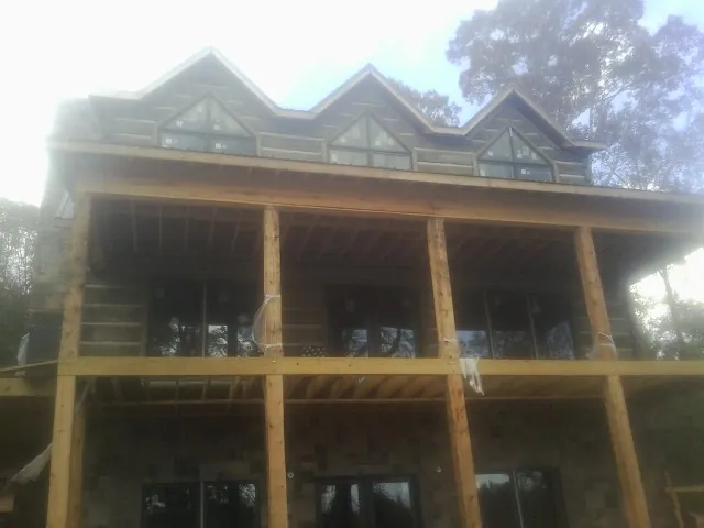 Dormers and porch framing on a large log home under construction — Roof Coating work by our crew in Wartburg