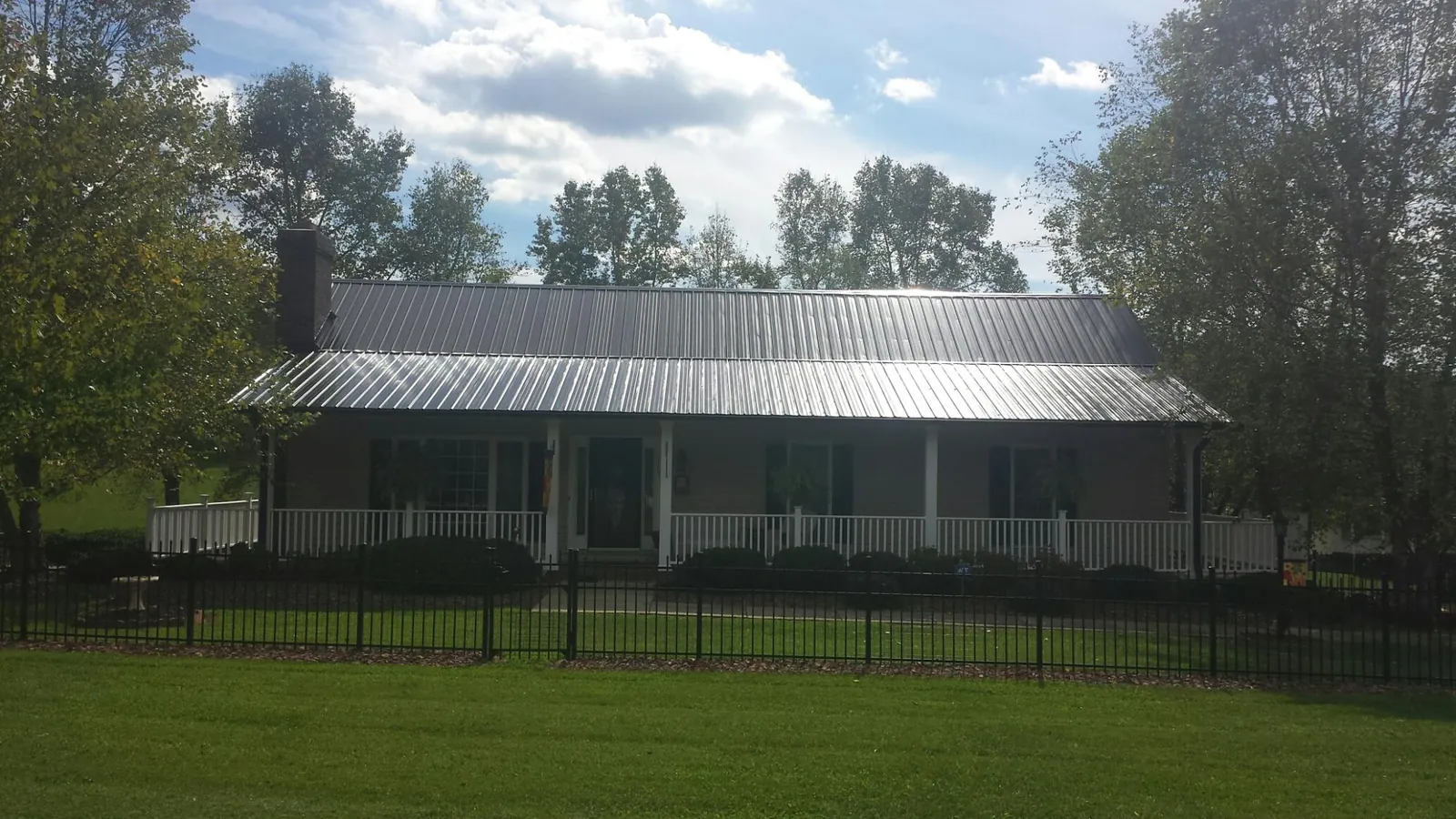 Gray metal roof on a brick ranch with a full width front porch in Wartburg
