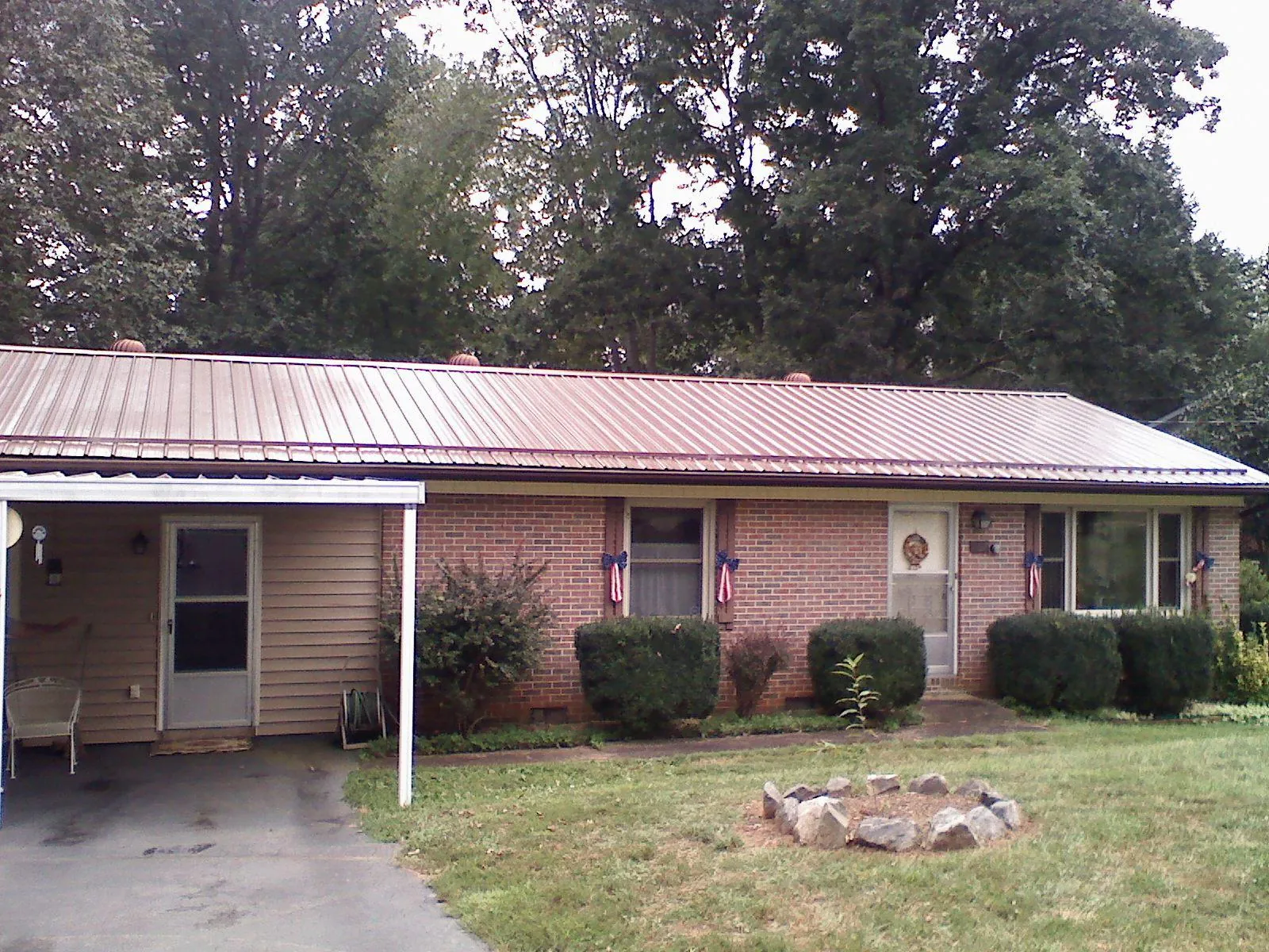 Bronze metal roof and carport on a brick ranch home — Roof Repair work by our crew in Wartburg