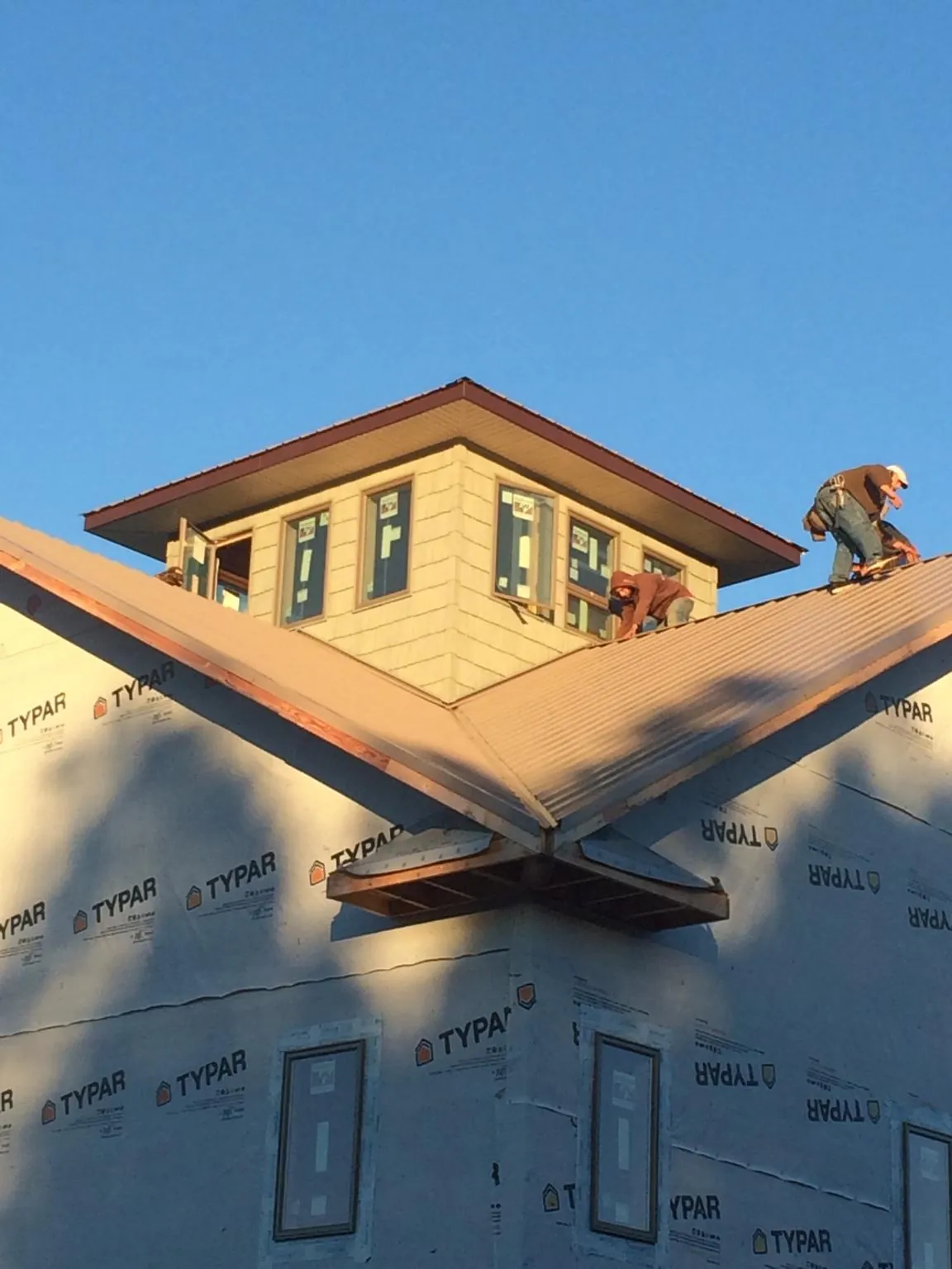 Roofers working around a rooftop cupola on a new metal roof at sunset — Roof Waterproofing in Wartburg by Roofing Brothers